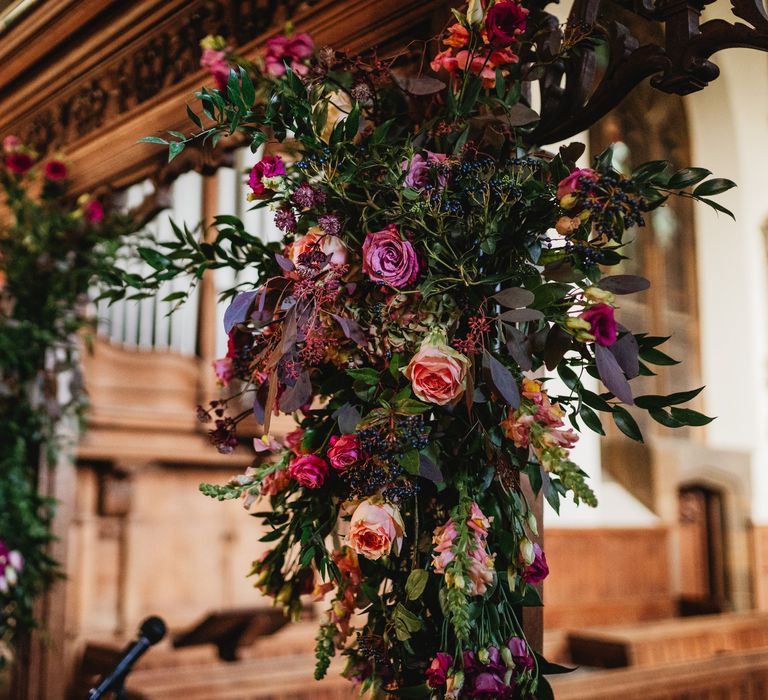 Pink floral bouquets surround the arch at altar in church