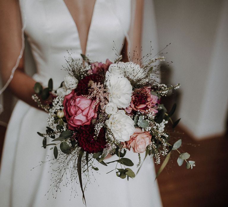 Bride holding pink and white rose wedding bouquet with leaf details