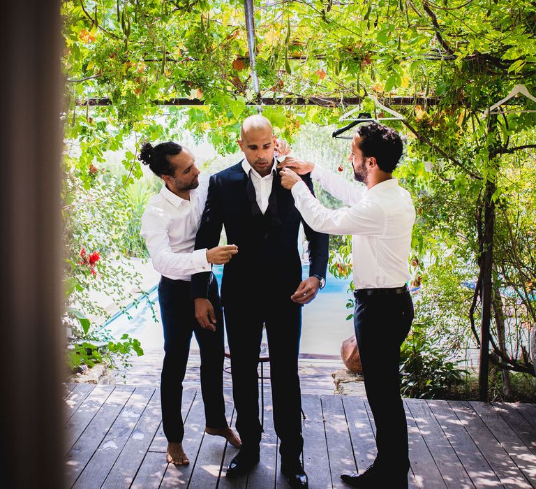 The groom being dressed into his navy blue Hugo Boss suit