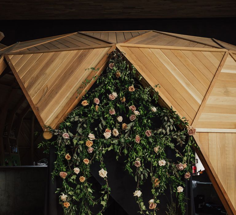 Ceremony altar wedding decor with black sheets, pink and green wedding flowers and candles in bottles on the floor 