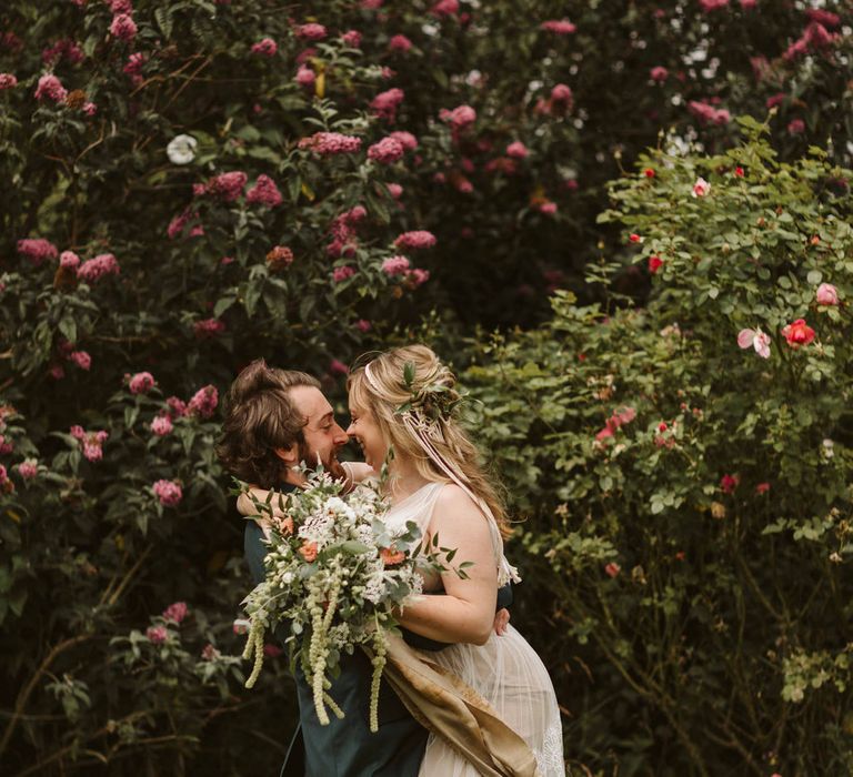 Groom picks up bride outdoors during botanical wedding