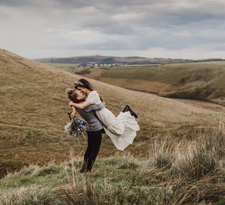 Same-sex couple lifting up the bride in the Peak District hills