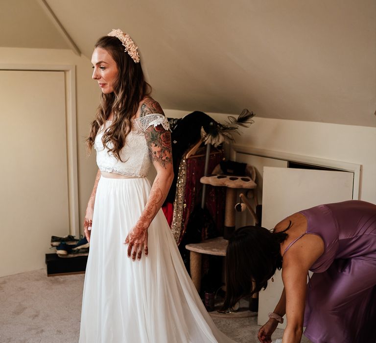 Bride stands in bedroom wearing two piece bridal outfit