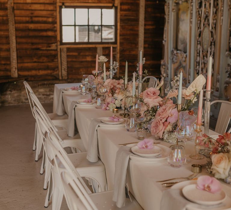 Pastel wedding theme table decor with white tableware, iridescent glassware, taper candles and floral centrepieces 