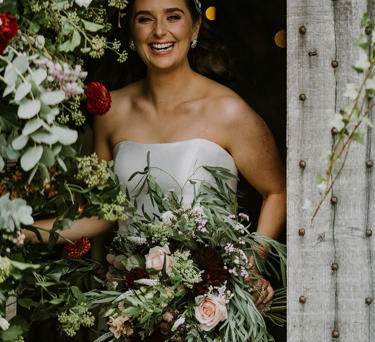 Bride in a strapless wedding dress holding a natural wedding flowers bouquet with foliage and roses 