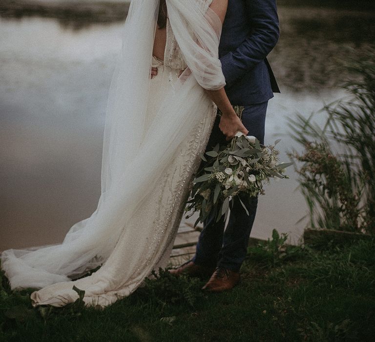 Bride & groom kiss in front of lake 