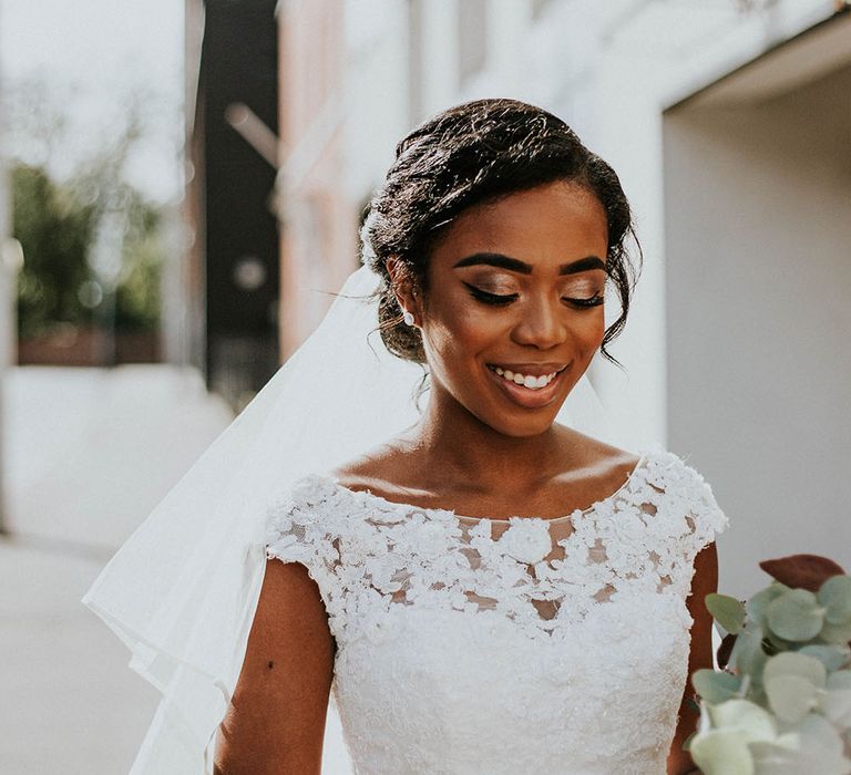 Classic bride in a lace wedding dress with slash neck, with elegant bridal updo and wedding makeup