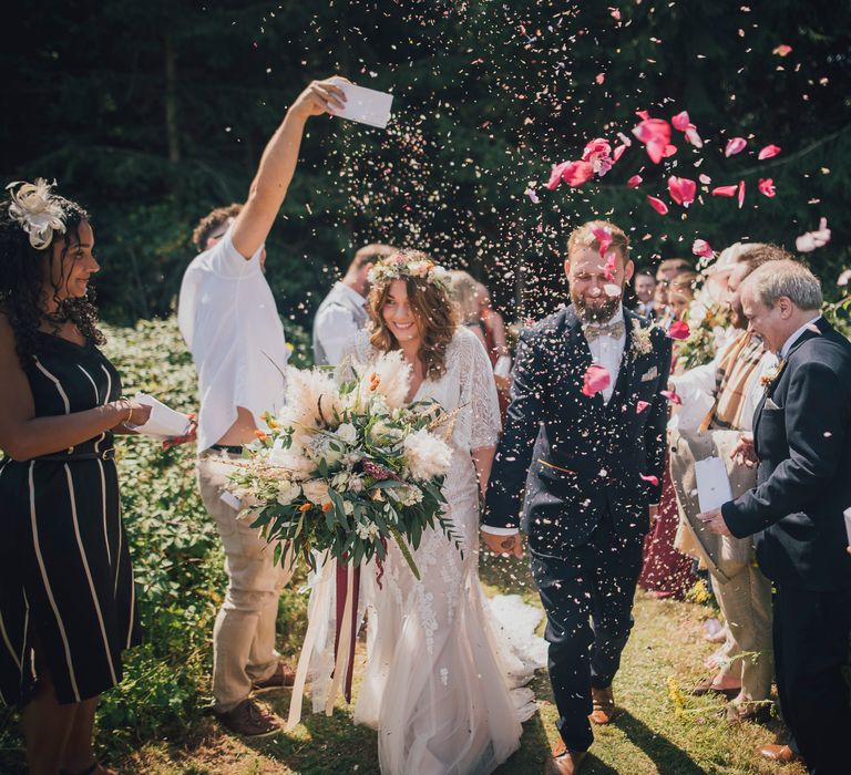 Bride & groom walk through confetti with one another after wedding ceremony