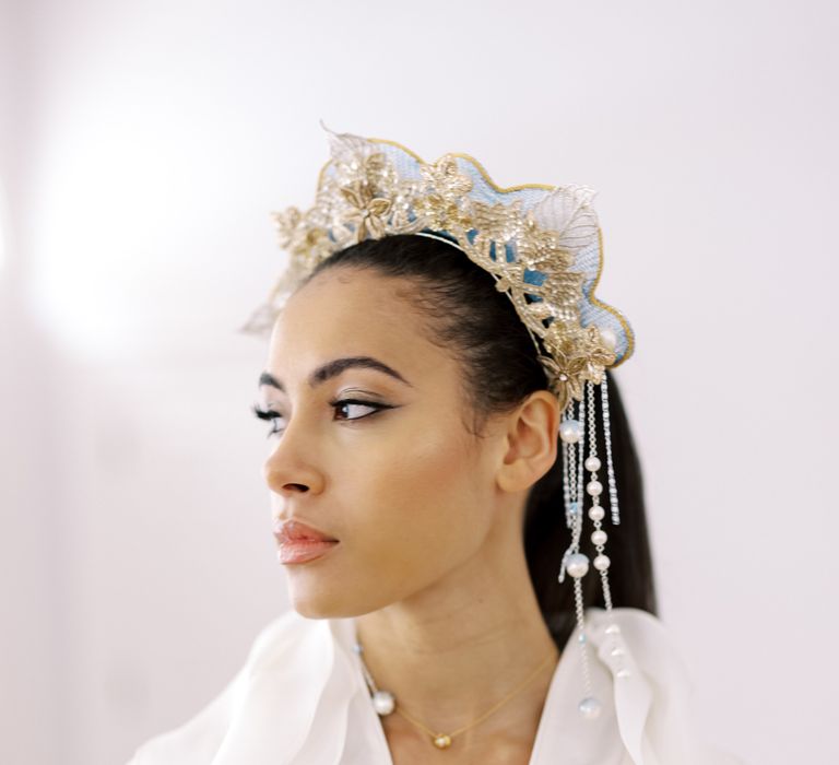 Bride looks to the side as she wears golden embroidered flower crown with peal embellishment falling to the side