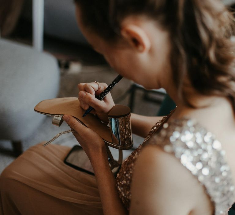 Bridesmaid writing in blue ink on the bottom of her shoe