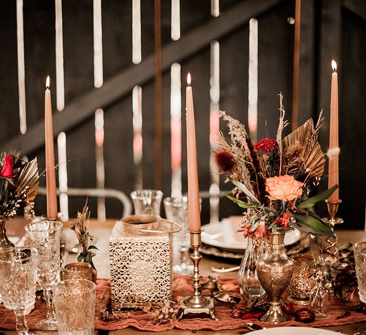 Moroccan inspired gold lanterns and vessels filled with orange and dried flower arrangements 