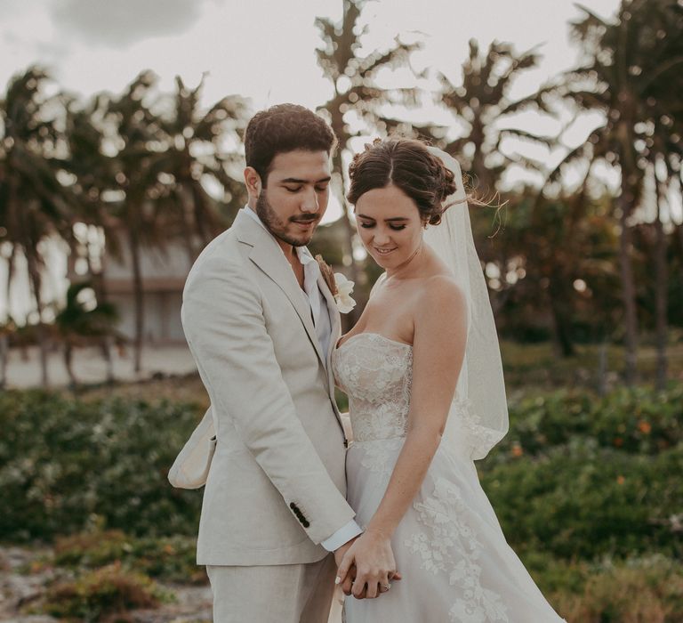 Bride & groom hold hands and look down on their wedding day in Mexico