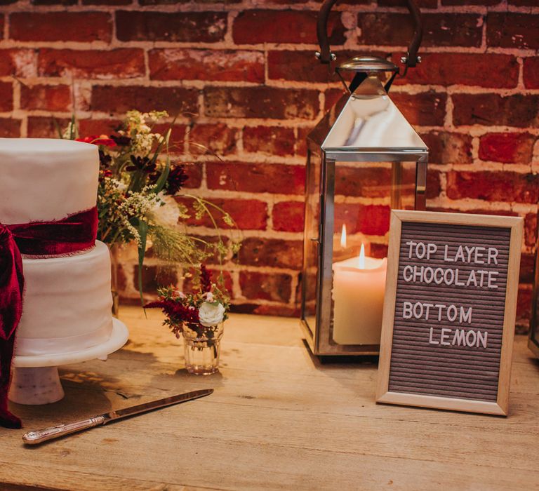 Two tier white iced wedding cake decorated with burgundy velvet ribbon with a chocolate and lemon flavoured layer 