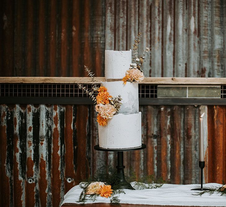 Three-tier buttercream wedding cake by The Little Kendal Cakery with orange flower decor 