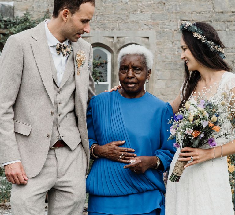 Bride & groom stand with family member on their wedding day