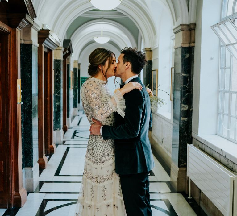 Bride & groom kiss in the Town Hall whilst bride wears Needle & Thread wedding dress 