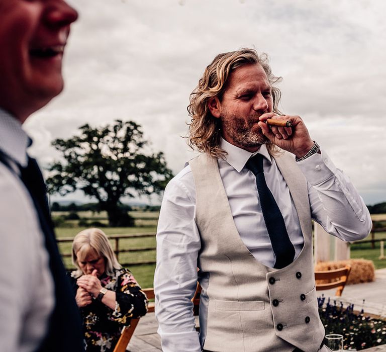 Groom enjoys cigar in pale waistcoat