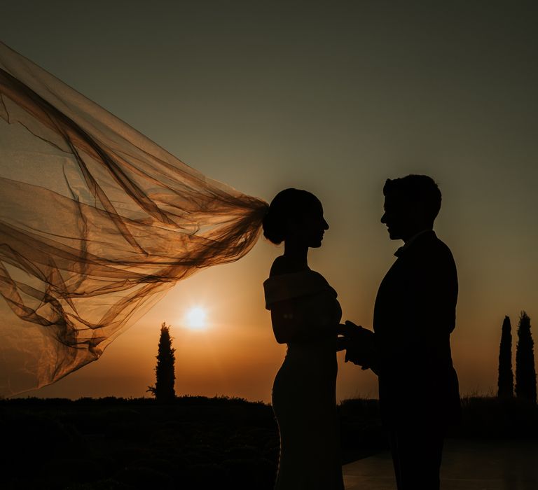 Shadow image of bride & groom during sunset as brides veil blows behind them on their wedding day | Hannah MacGregor Photo & Film