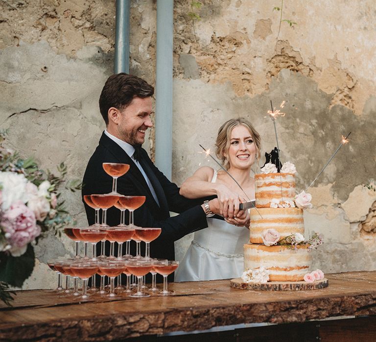 Bride and groom cutting their naked sponge wedding cake at their French destination wedding 