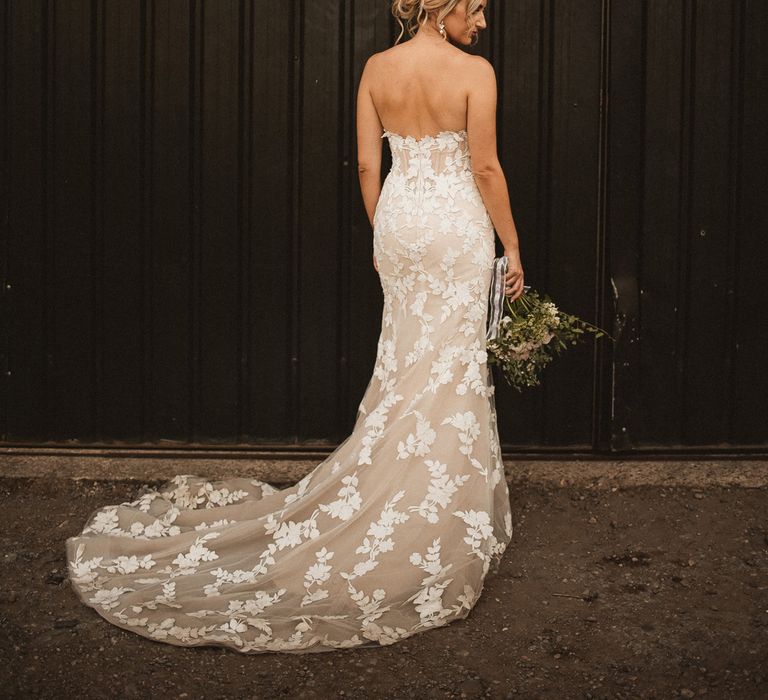 Bride with curled wedding updo in white off the shoulder Enzoani wedding dress with train stands holding bouquet at Inkersall Grange Farm wedding