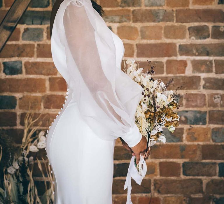 Boho bride in a fitted wedding dress with sheer long sleeves and buttons down the back standing at the hexagonal altar at Brickhouse Vineyard