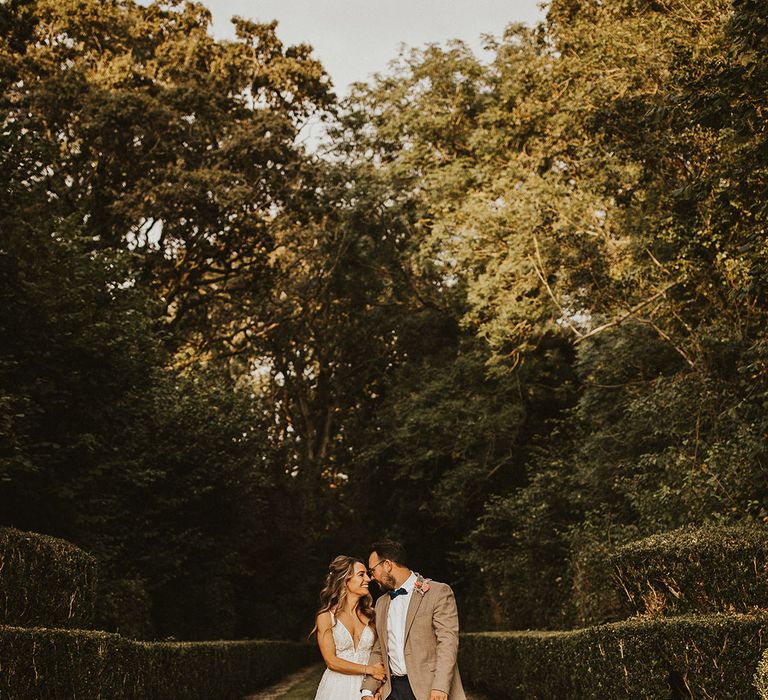 Bride & groom kiss outdoors on their wedding day surrounded by greenery 