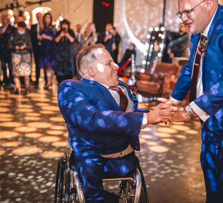 Grooms in blue wedding suits dance at The Chainstore Trinity Buoy Wharf wedding venue