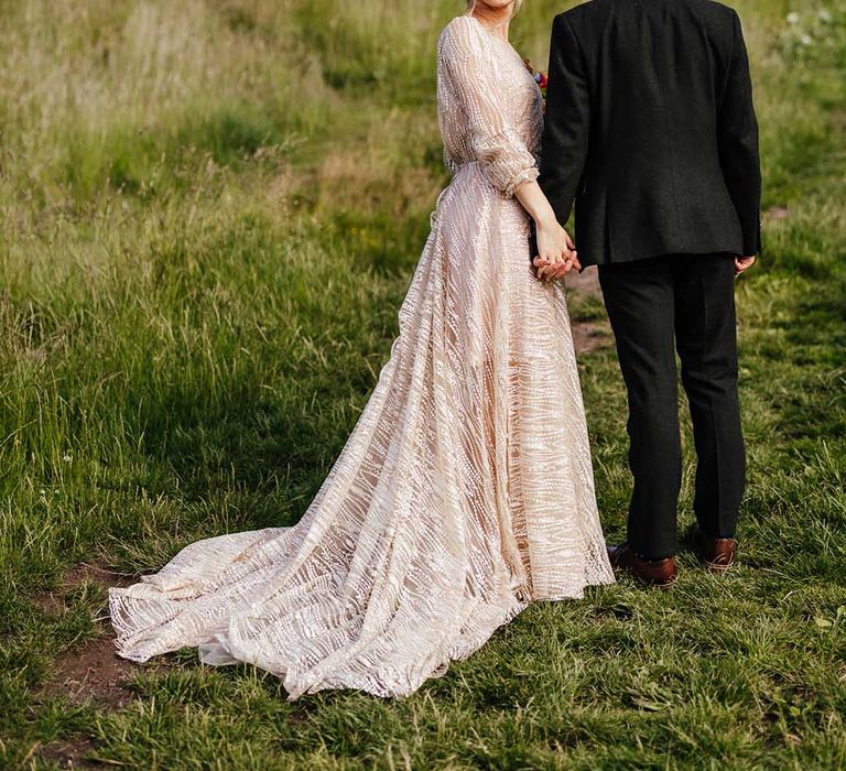 Bride & groom walk hand in hand up a hillside in Scotland on their wedding day