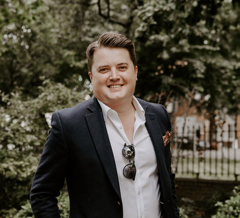 Groom in stone chinos, white open collar shirt and blue blazer for relaxed registry office wedding