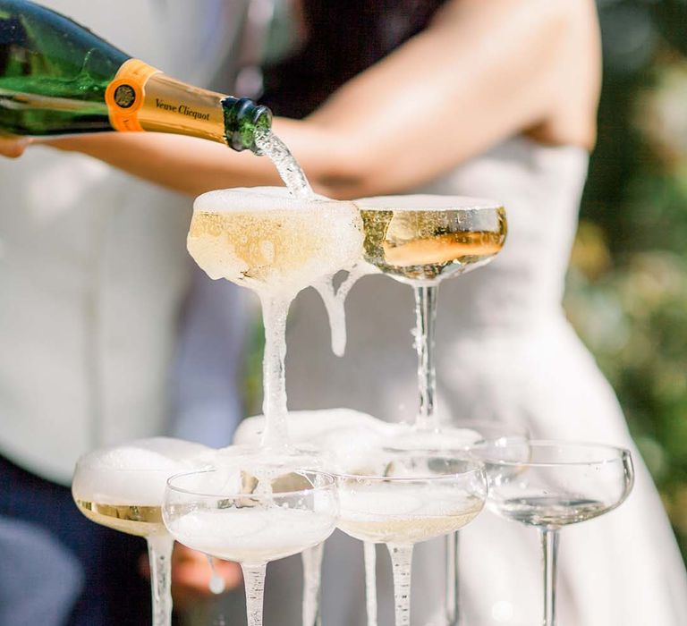 Bride & groom pour champagne into glasses for champagne tower 