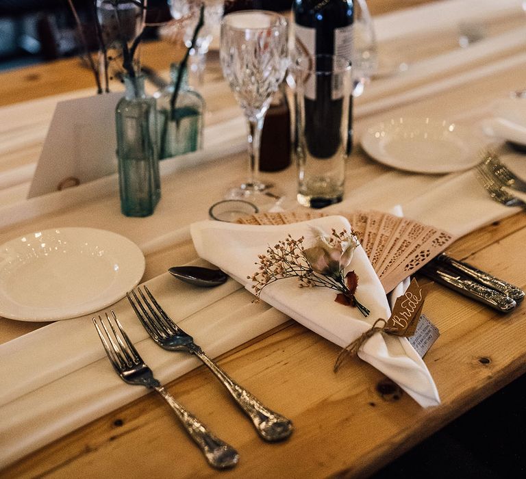 Place setting with wooden fan favours and dried flower decor 