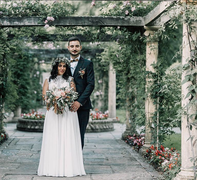 bride & groom stand beneath pergola on their wedding day