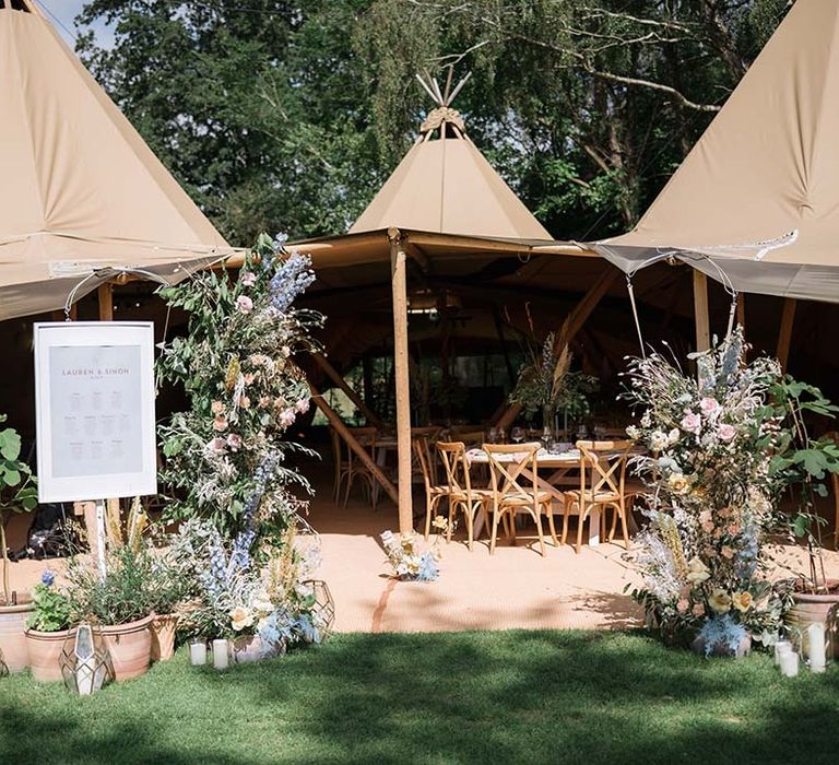 Buffalo tipi reception area with welcome wedding sign and large pastel flower displays with summer colours