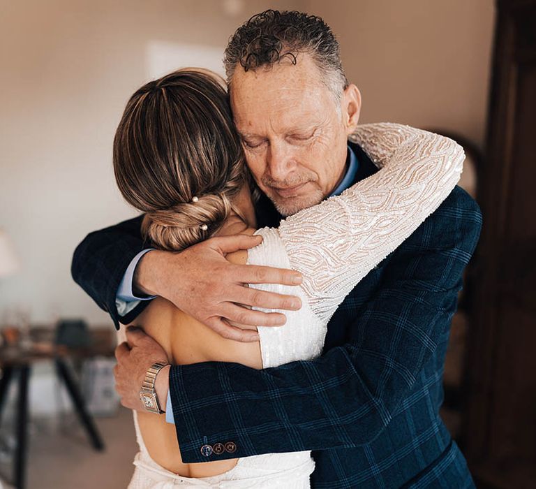 Father of the bride gives the bride a big hug with bride wearing updo with pearl hair pins