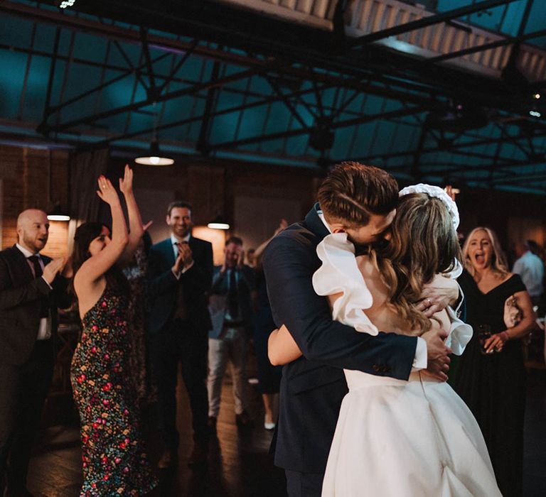 Bride and groom share a loving embrace after they complete their first dance and guests applaud them