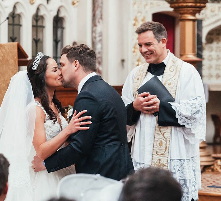 Bride and groom share their first kiss as a married couple after their church wedding ceremony 