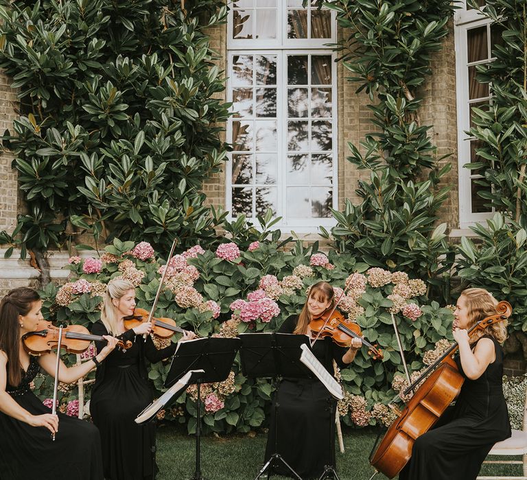 Live wedding music seated outside the wedding venue while guests socialise 