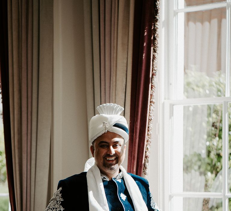 Groom wears white and blue Sherwani on his wedding day complete with embellishment 