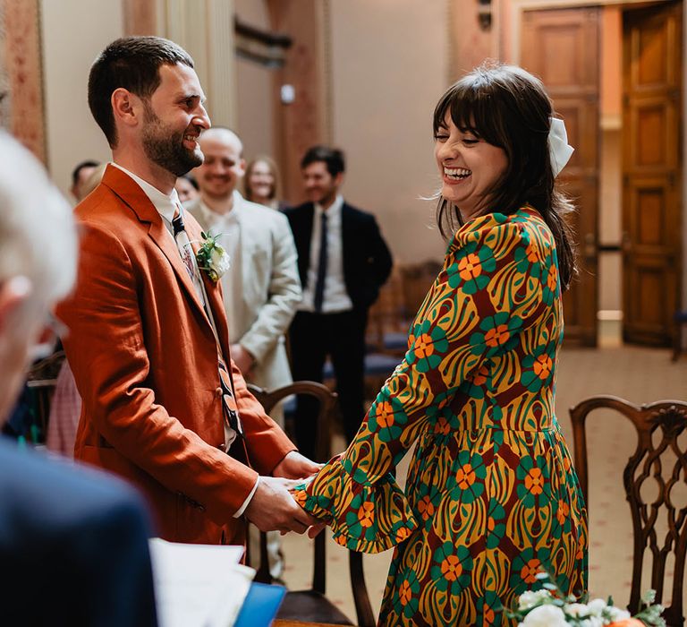 Bride & groom hold hands during wedding ceremony in Bristol for colourful and relaxed day 