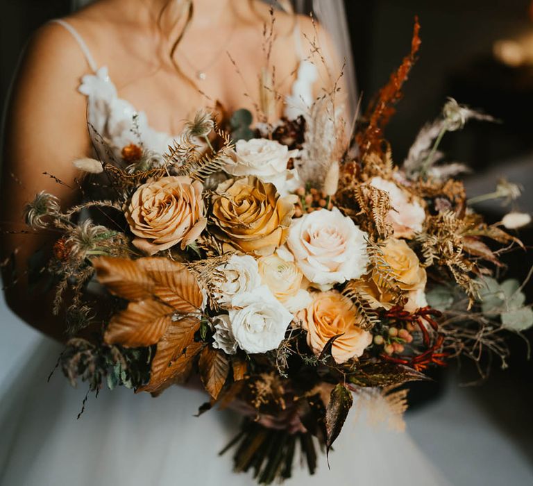 Autumnal wedding bouquet with white and toffee roses, autumn leaves and dried grasses 