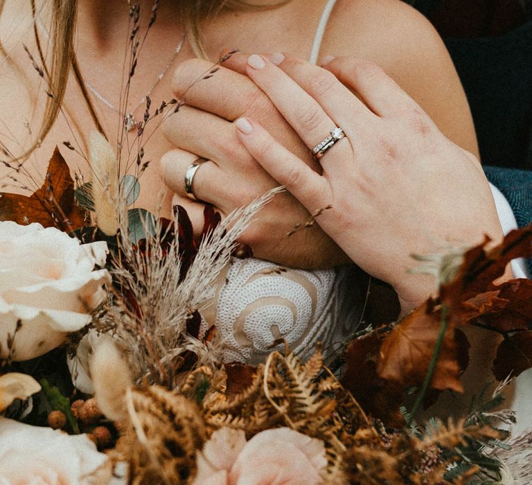 Bride wearing a silver wedding band and diamond engagement ring with groom wearing a plain silver wedding ring 