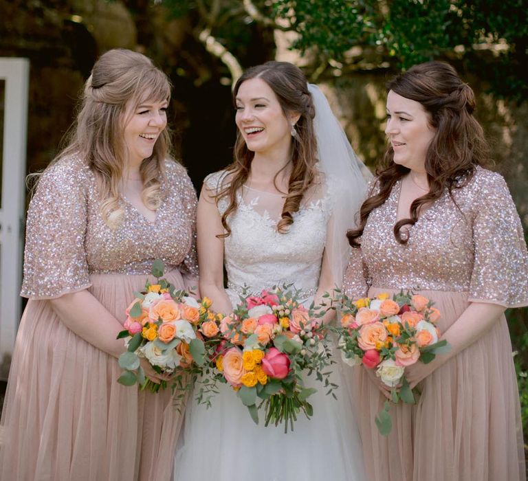 Bridesmaids in short sleeve pink embellished bridesmaid dresses with the bride in a lace wedding dress