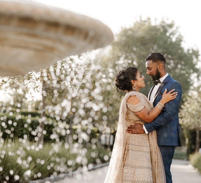 Bride wears gold and embellished traditional Sri Lankan wear whilst embracing her groom 