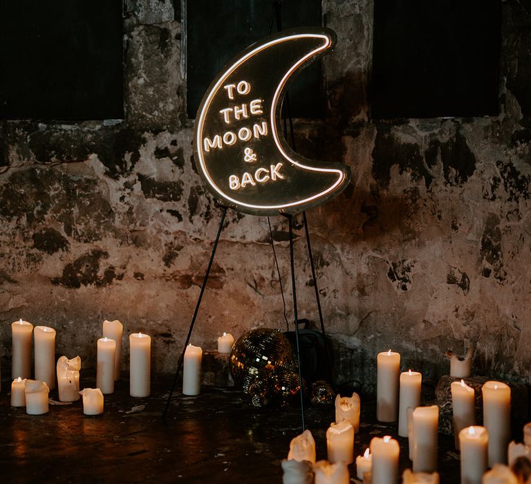 Celestial wedding lighting created by a moon neon sign and candles