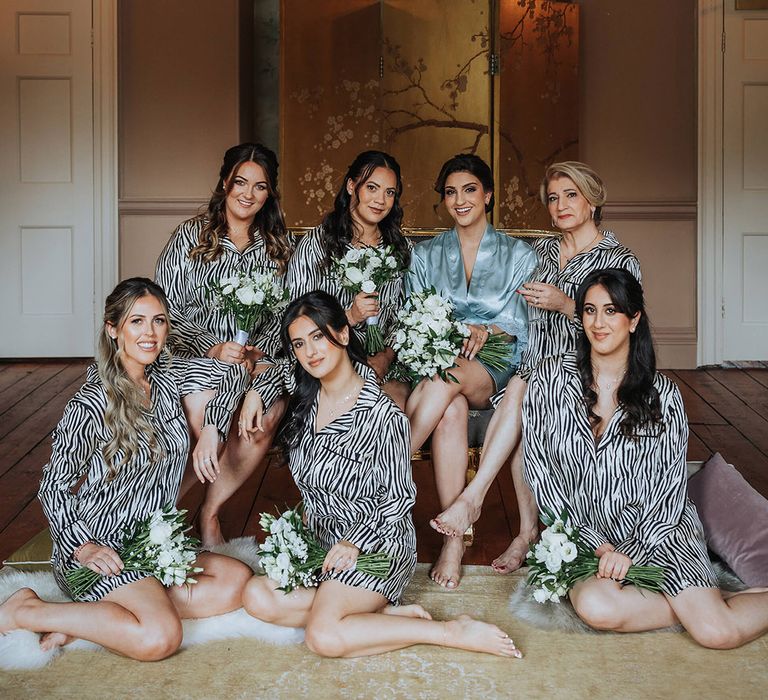 Bridesmaids and mother of the bride in black and white striped pyjamas with the bride in a blue satin robe as they get ready for the wedding 