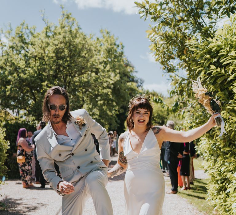 Bride and groom in complimenting ASOS outfits, black high top converse and sunglasses dancing at The Reid Rooms wedding venue