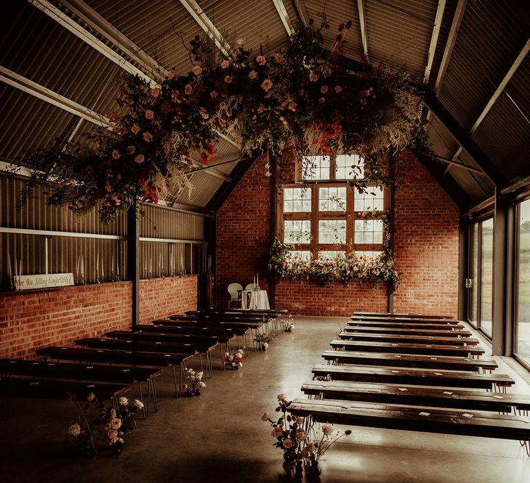 The Giraffe Shed wedding venue with large hanging floral and foliage decorations and floral arrangements down the side of the aisle