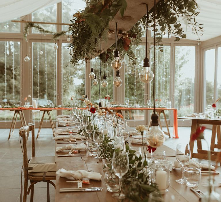 Hanging floral installation with festoon lighting over the wedding table at Trevenna Barns wedding venue in Cornwall 