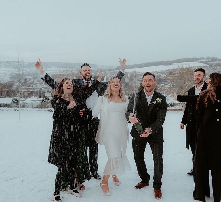 The groom sprays champagne as the bride and the wedding guests celebrate the new marriage together 