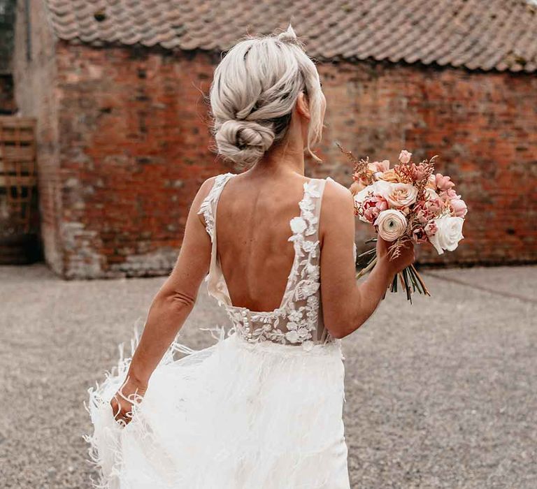 Bride in Nori Ivy wedding dress with low back and fringe overlay holding dried blush garden rose, peony and dried flower bridal bouquet 